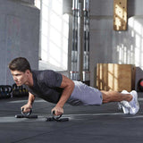 Male uses push up bars in gym to complete a deficit pushup on his toes.